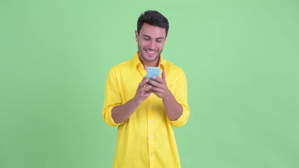 Happy Young Hispanic Businessman Thinking While Using Phone