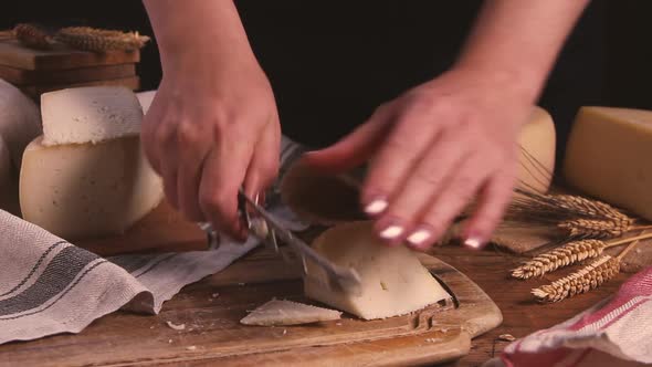 Women cut fresh homemade cheese on a wooden board with a cheese knife close up