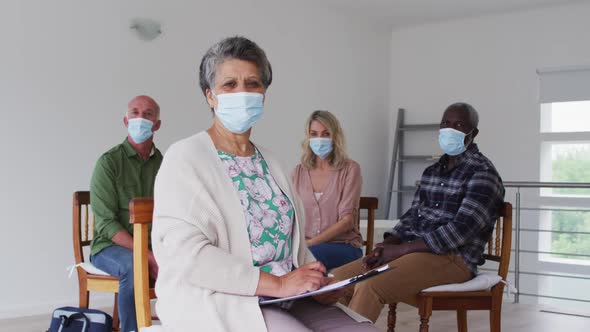 Two diverse senior couples sitting in circle having therapy conversation at home looking at camera