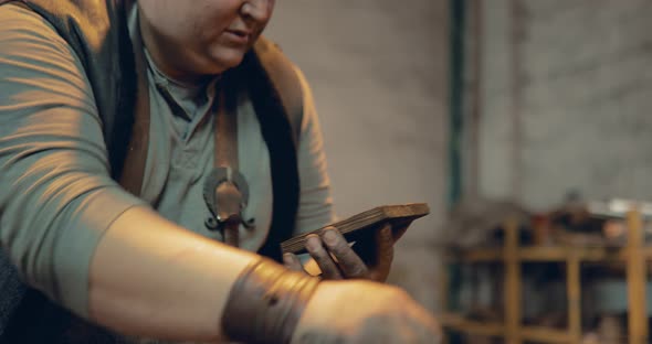 Blacksmith is Holding a Wooden Board