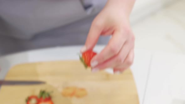 Strawberries are Cut Into Pieces on a Wooden Cutting Board to Decorate Desserts