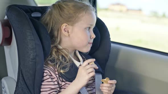 Little Girl Eating Cookie in Car