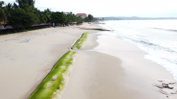 Aerial, beach coastline with giant sandbag barricade to prevent rising sea level