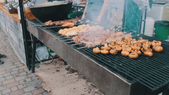 Shish Kebab and Mushrooms on Skewers Cooked on Barbecue at Street Food Festival