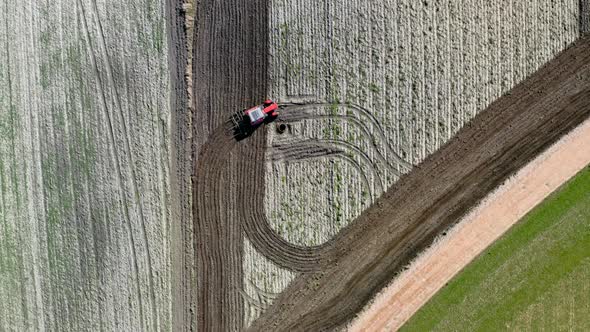 Red tractor plowing a spring field in Poland, aerial view