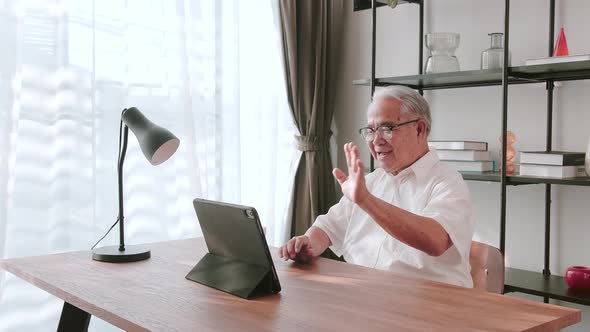 Mature Asian senior making video call through his digital tablet. Accessibility and digital inclusio