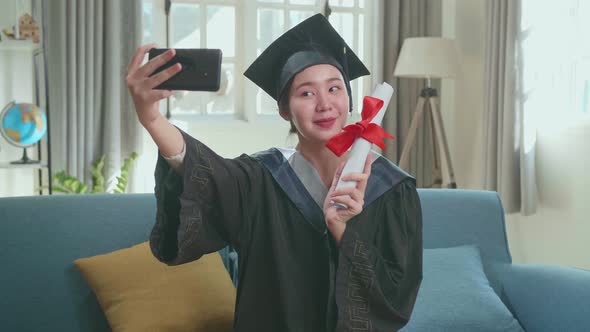 Woman Taking A Selfie While Wearing A Graduation Gown And Cap, Hand Holding University Certificate