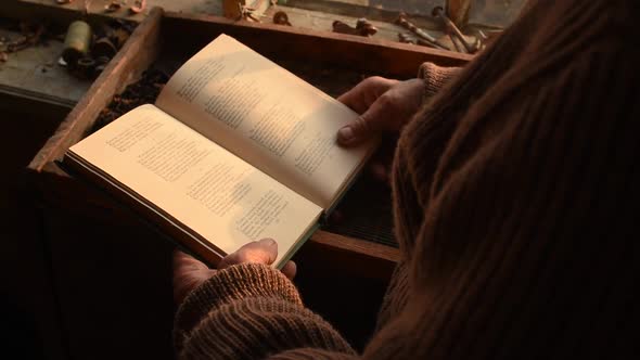 Man Glasses Picks Up Old Book in Dust Read in House Window