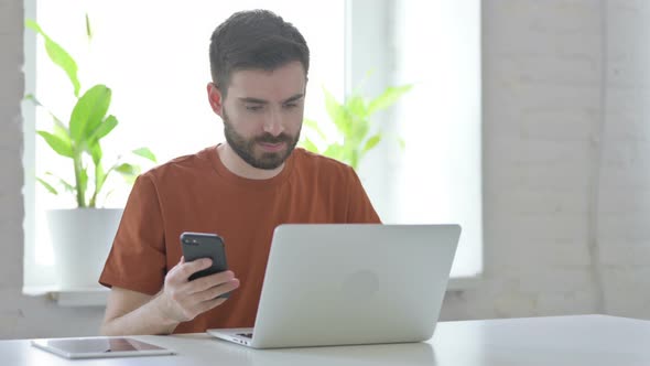 Young Man Using Smartphone at Work