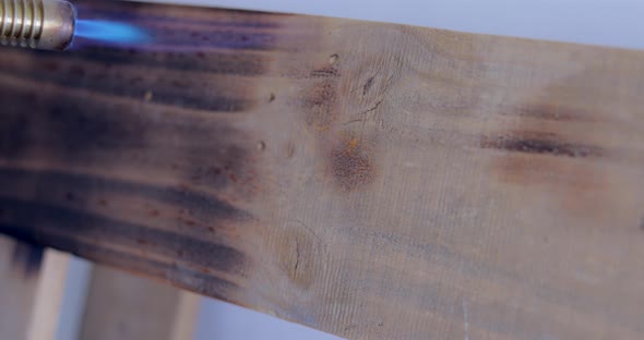 Person Using Butane Blowtorch To Burnt The Surface Of Wooden Pallet. - close up