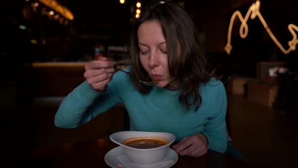 Woman Is Tasting Soup in Cafe at Winter Evening, Slow Motion Shot, Lady Alone