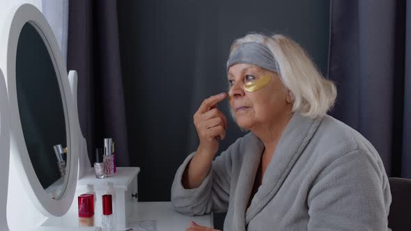 Old Senior Elderly Woman Grandmother Applying Anti-wrinkle Eye Patch, Putting Makeup on at Home