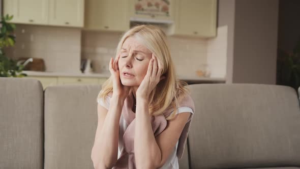 Woman Suffering From Stress or a Headache Grimacing in Pain As She Holds the Back of Her Neck with