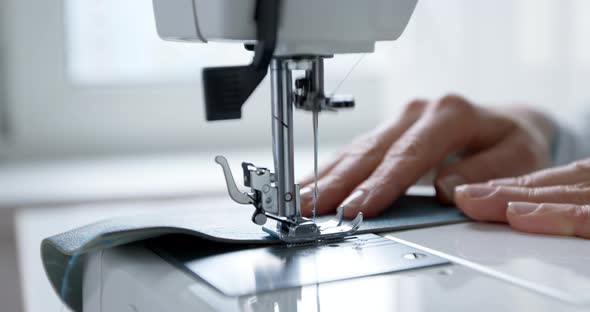 A seamstress works on a sewing machine. Close-up of a needle and thread. Clothes designer. Tailor.