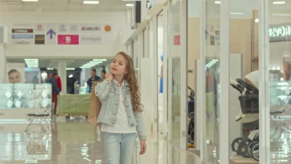 Cute Little Girl Carrying Shopping Bag, Walking at the Mall