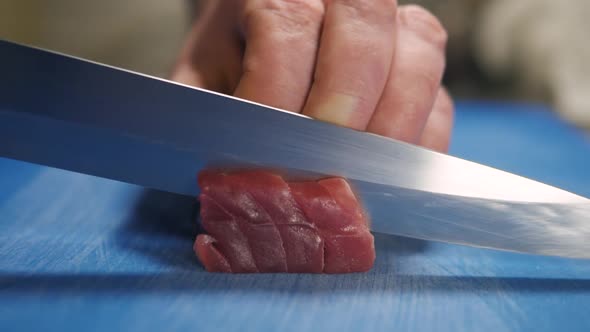 Close Up Macro on the Hands of the Japanese Sushi Sashimi Chef 's Knife Slice the Raw Tuna Salmon