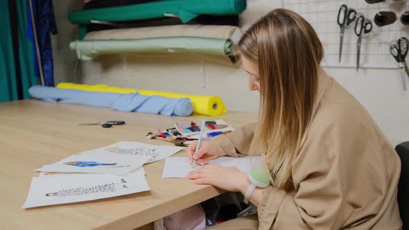 Female designer using pencil and sheet of paper for fashion sketches. Tailor woman creating design