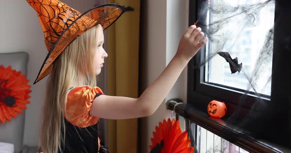 Cute Caucasian Little Girl with Blonde Hair Seven Years Old in Witch Dress and Hat Having Fun and
