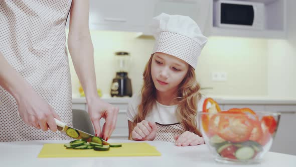 Pretty Child Watching How Her Mother Cooking Fresh Salad