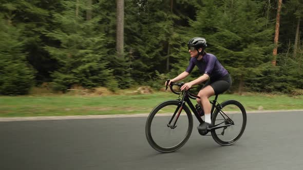 Woman cycling on road bicycle in forest