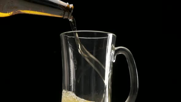 Pouring blonde beer slow motion on pint glass black background