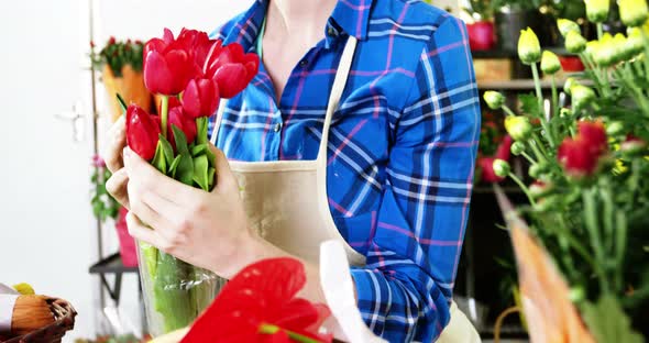 Female florist holding a bunch of red rose in flower shop