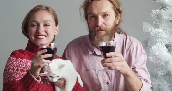 Portrait of Caucasian Family of Young Couple with Pet White Cat Holding Glasses of Wine in Hands