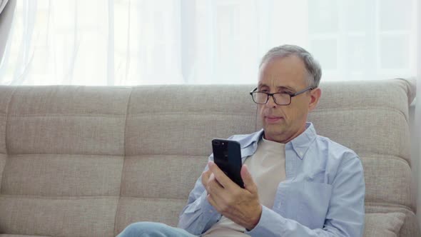 Elderly Man Rejoices Looking Into Smartphone