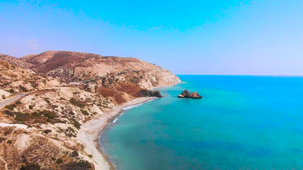 Slow aerial view flying along the coast of pafos away from Aphrodite's Rock on the coast of Paphos C