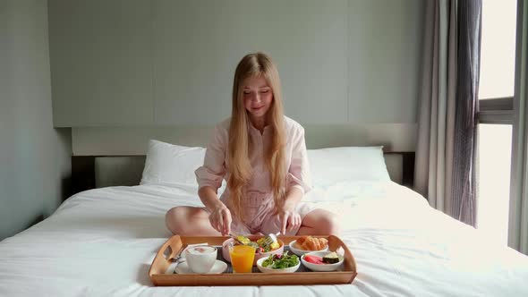 Breakfast in Bed  Happy Woman Sitting on Bed in Hotel Drinking Coffee