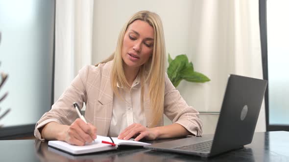 Concentrated Businesswoman in Smart Casual Wear Using Laptop for Watching Online Webinar