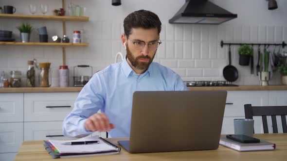 Serious Adult Caucasian Businessman Working Online Using Laptop at Home Office