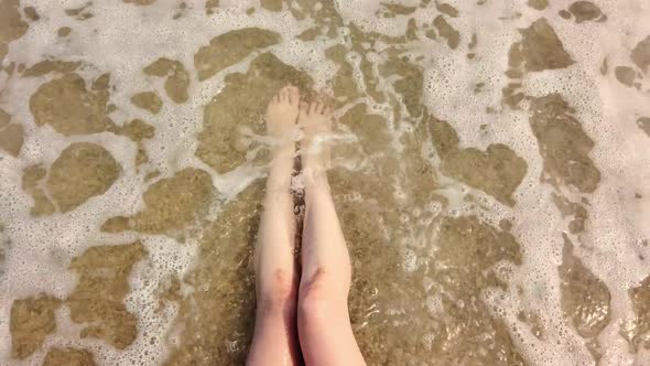 Female Legs in the Waves of the Sea Surf