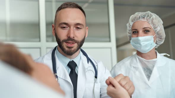 Doctor and Nurse Visiting Young Woman at Hospital