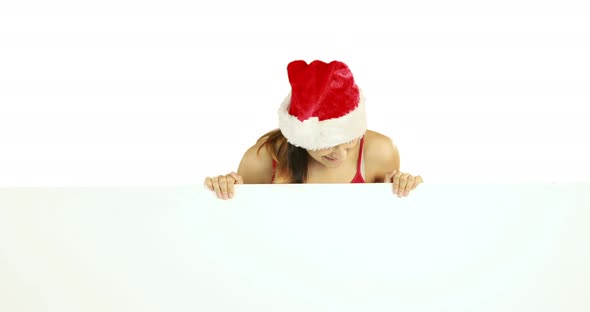 Beauty brunette in santa hat showing white poster 4k