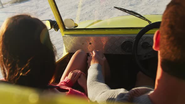 Happy caucasian couple sitting in beach buggy by the sea hugging