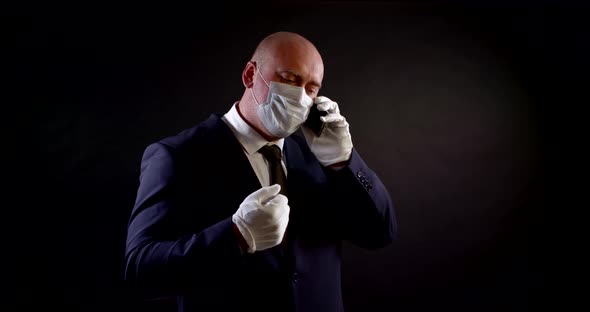 Portrait of a Man in a Business Suit, a Disposable Mask and White Protective Gloves on a Black