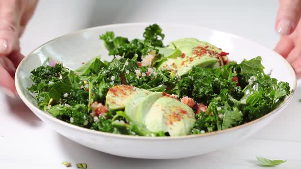 Healthy salad with kale, quinoa, nuts and avocado in white bowl. 