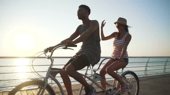 Portrait of a Mixed Race Couple Riding on Tandem Bicycle Outdoors Near the Sea Slow Motion