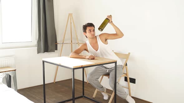 Male Alcoholic with an Empty Bottle at the Table of the House