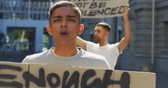 Two mixed race men on a protest march holding placards raising hands and shouting