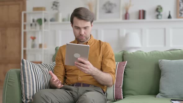 Young Man having Loss on Tablet on Sofa