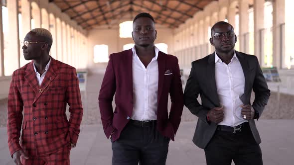 Stylish black friends in suits in building passage