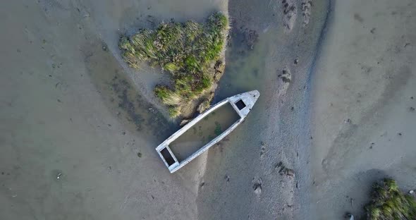 Broken Motorboat Hull By Shrubs on Polluted Sandy Land