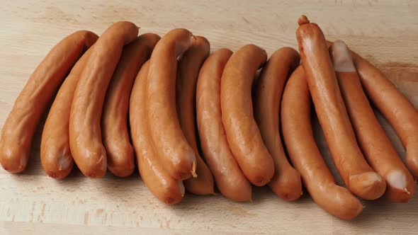 Thin long pork sausages on the wooden cutting board