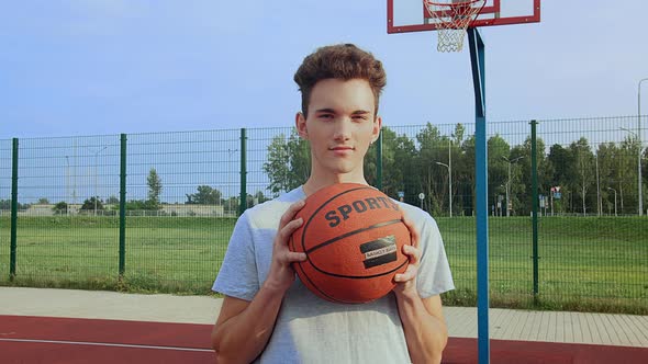 Portrait of a Athlete a Guy on a Sports Field with a Basketball in His Hands Looking at the Camera