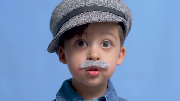 Child with a Gray Gray Mustache and a Hat Stands in the Studio