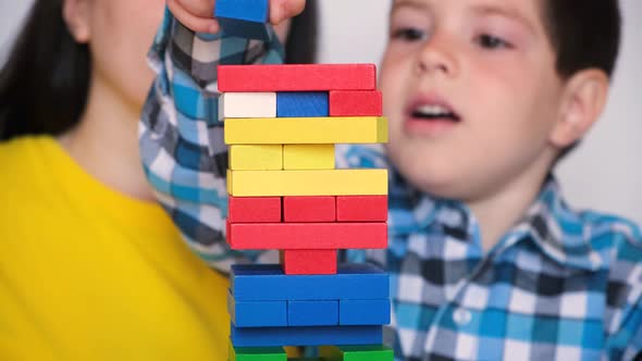 Mother and Son Play a Board Game of Jenga Carefully Pulling Colorful Blocks From the Tower