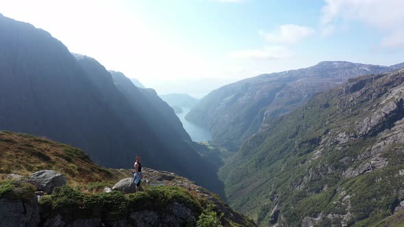 Beautiful woman standing on top of cliff surrounded by dramatic landscapes and complete wilderness i