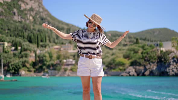 Young Happy Carefree Woman in Straw Hat Standing on Turquoise Sea Bay Background and Enjoying